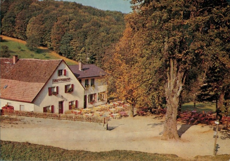 Der Schönberghof mit roten Fensterläden und der großen Kastanie vor dem Haus