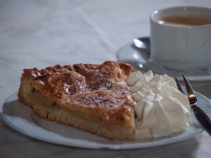 Ein Stück Apfelkuchen mit Sahne und eine Tasse Kaffee