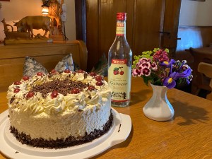Schwarzwälder Kirschtorte mit einer Flasche Kirschwasser