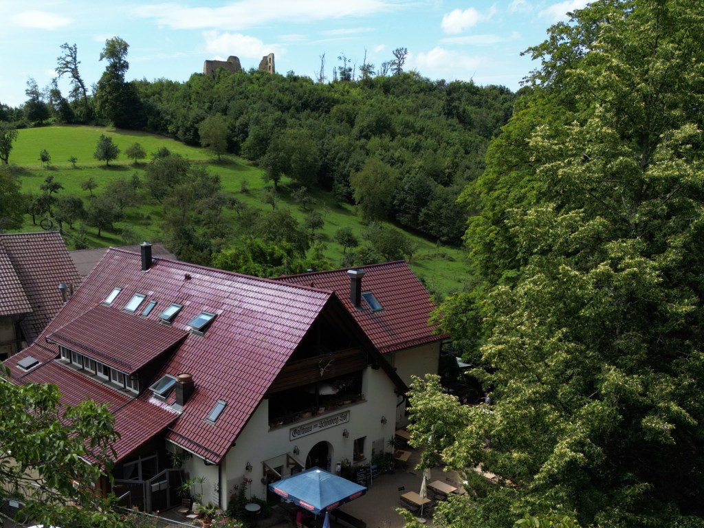 Der Schönberghof von der Seite mit Terrasse, oben auf dem Hügel die Ruine Schneeburg