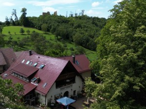 Der Schönberghof von der Seite mit Terrasse, oben auf dem Hügel die Ruine Schneeburg