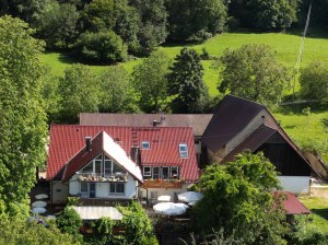 Der Schönberghof mit Terrasse und Scheune zwischen Wiesen und Wald